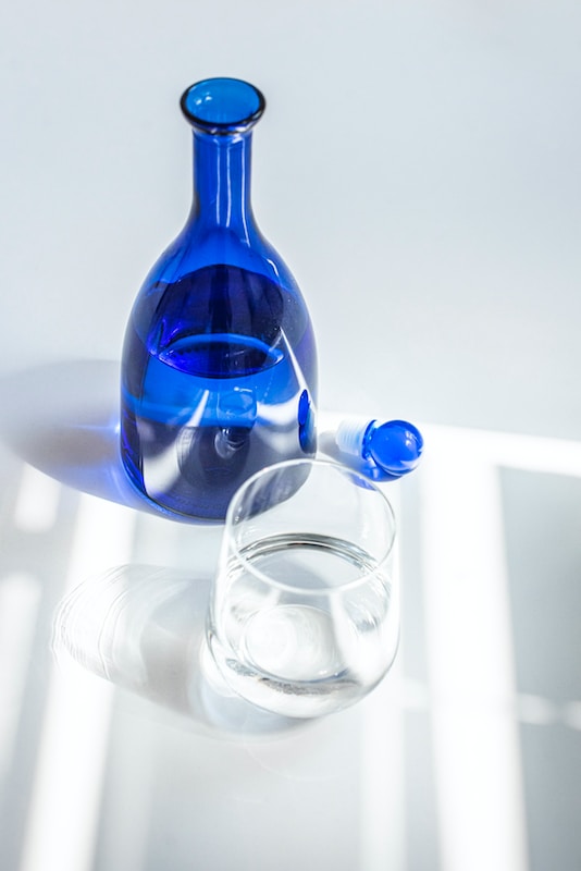 blue glass bottle beside clear drinking glass
